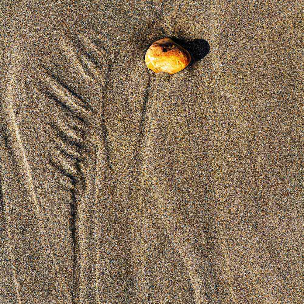 strands | A yellow stone, sand and shadows like vertebrae on a Breton beach