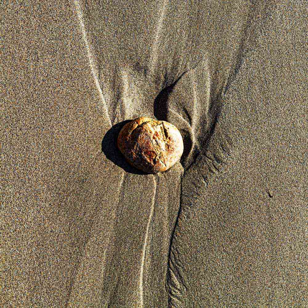strands | A yellow stone, sand and shadows like vertebrae on a Breton beach