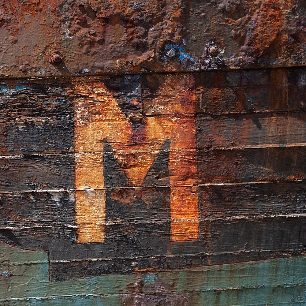 Camaret-sur_mer | The registration number M on side of a rotting hulk of a fishing boat with peeling rusty green, brown and yellow paint
