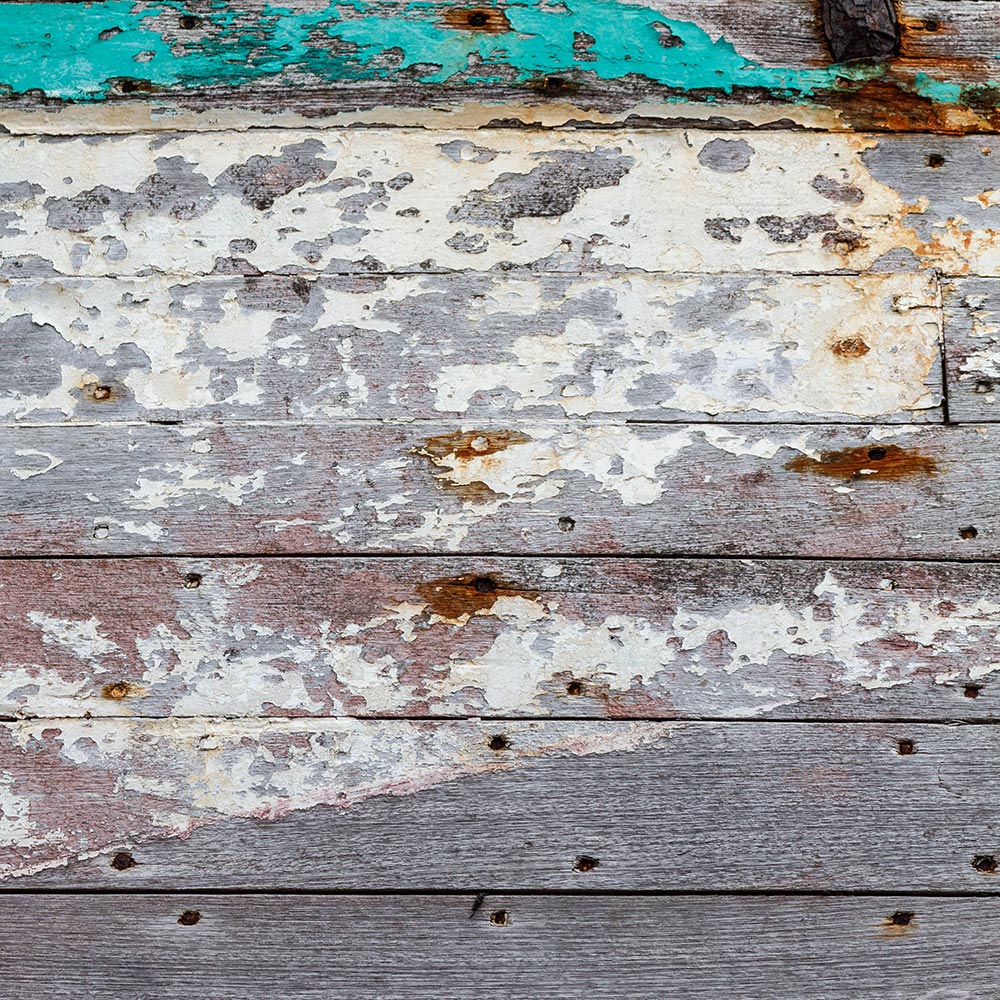 Camaret-sur_mer | The side of a rotting hulk of a fishing boat with peeling rusty turquoise cyan and red paint